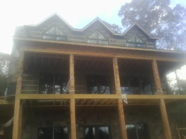 Dormers and porch framing on a large log home under construction — Roof Coating work by our crew in Eldred