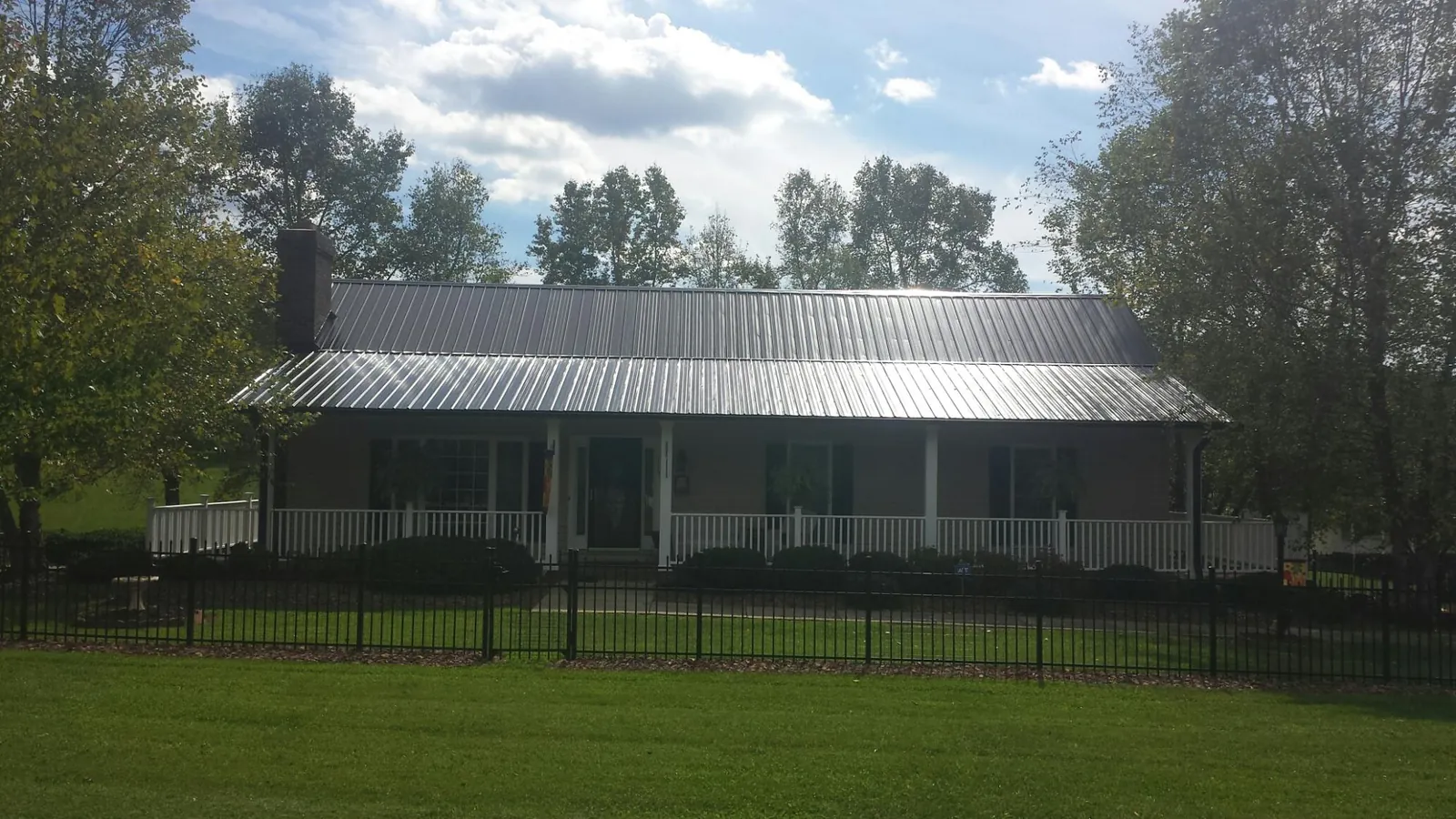 Gray metal roof on a brick ranch with a full width front porch — Gutter Guard Installation work by our crew in Eldred